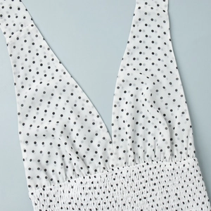 Detailed view of deep V-neckline and smocked waist on white polka dot summer dress