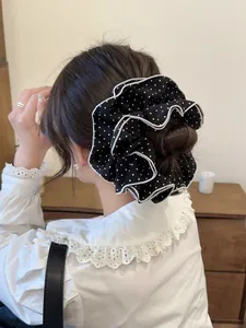 Detail of a large polka dot hair scrunchie with ruffled edges worn on a bun hairstyle