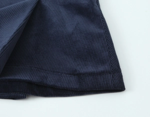 Close-up detail of dark blue corduroy fabric texture and stitching on the mini skirt top