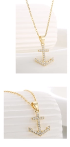 Macro detail of a gold anchor pendant necklace featuring micro-pave sparkling crystals
