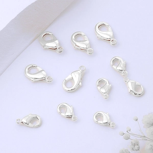 Close-up of polished silver lobster clasps for DIY jewelry making on white background