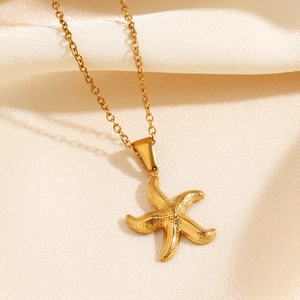 Collier avec pendentif étoile de mer dorée texturée sur fond de soie beige