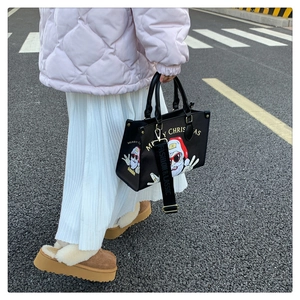 Lifestyle shot of a black Christmas tote bag featuring Santa Claus print on a city street