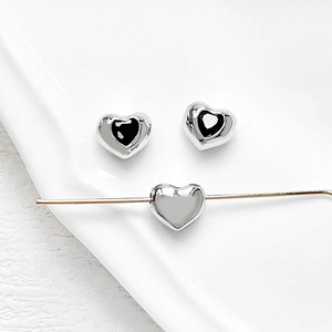 Macro detail of heart-shaped spacer beads with black enamel and 18k gold plating
