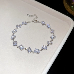 Macro detail of a silver bracelet featuring rectangular clear gemstones on a jewelry tray