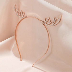 Detailed view of a rose gold reindeer antler headband with rhinestones on pink silk fabric