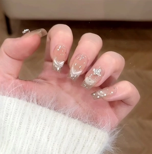 Detail of nude cat-eye press-on nails with 3D silver stars and French glitter tips