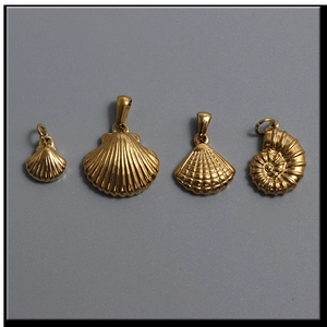 Detailed macro view of four 18K gold nautical pendants featuring shell and nautilus designs