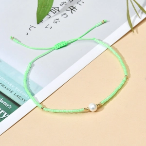 Detailed macro of a green beaded bracelet with a natural pearl and golden spacers