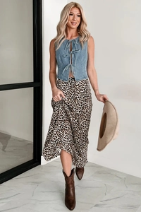 Detailed full-body street style look of a blue lace-up denim vest with a leopard print skirt