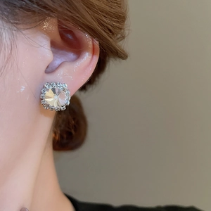 Close-up of model wearing silver round zircon stud earrings with sparkling pavé crystals