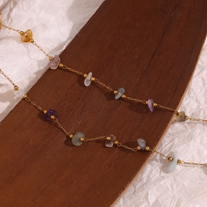 Macro detail of 18K gold-plated chain with colorful irregular natural stones and minerals