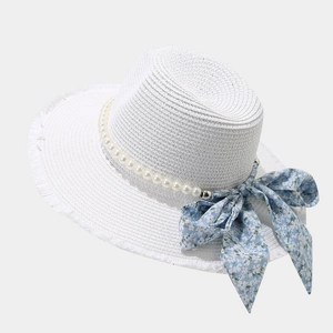 Detailed macro view of white raffia sun hat with pearl chain and blue floral bow ribbon