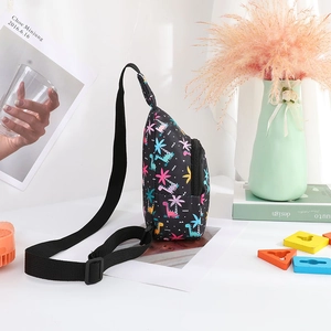 Detail view of children's dinosaur print nylon chest bag with adjustable strap on desk