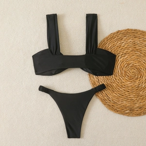 Détail d'un ensemble bikini noir avec texture froncée sur un tapis de plage tissé