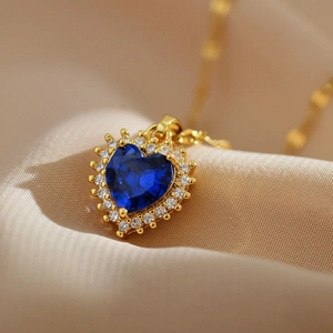 Blue heart-shaped sapphire pendant necklace with diamond halo on champagne silk background