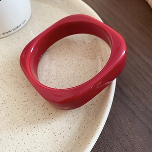 Detail of red square acrylic resin bangle with glossy finish on a ceramic plate