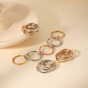 Polished gold, silver and rose gold stacked interlocking chain rings on textured surface