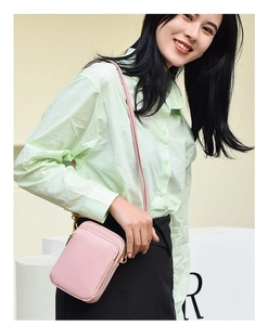 Lifestyle shot of a small pink crossbody phone bag with zipper and slim shoulder strap