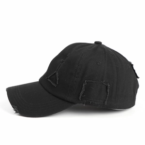 Close-up of distressed black cotton baseball cap with worn holes and geometric patches