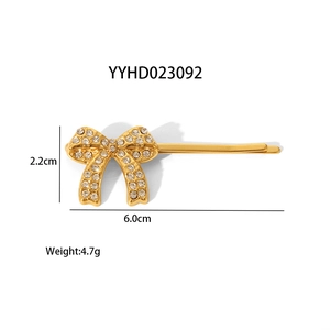 Dettaglio di fermaglio a fiocco dorato con strass, dimensioni 2,2 cm per 6,0 cm mostrate