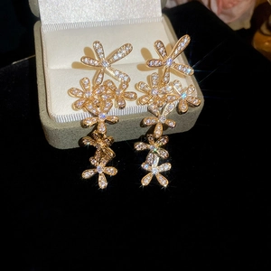 Detailed view of layered gold flower earrings encrusted with sparkling zircon stones