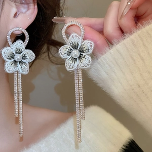 Détail de boucles d'oreilles fleur en broderie avec perle et pampilles scintillantes