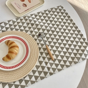 Gros plan d'un set de table rectangulaire en tissu avec des triangles géométriques gris et blanc