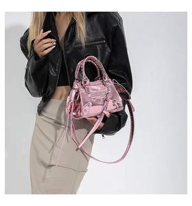 Detail of pink metallic crossbody bag with rivets and fringes on a fashion model