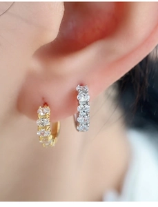Macro shot of silver and gold hoops with sparkling zircons worn on the earlobe