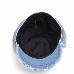 Macro view of blue denim newsboy hat showing frayed edges and internal adjustment cord