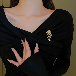 Elegant gold plated dragon brooch with sparkling crystals on black sweater background
