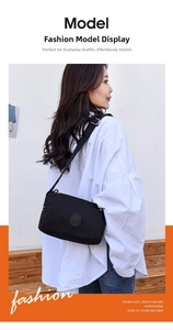 Detail of black nylon crossbody bag with adjustable strap worn by model on outdoor steps