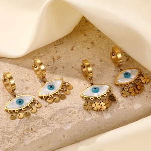 Detail of gold evil eye earrings with cat eye stone and clover coin charms