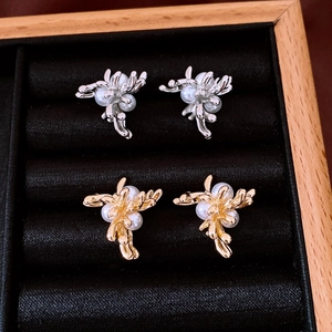 Close-up of gold and silver flower stud earrings with white pearls in a black velvet box