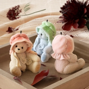 Three cute teddy bear scented candles in different colors placed on a modern concrete tray