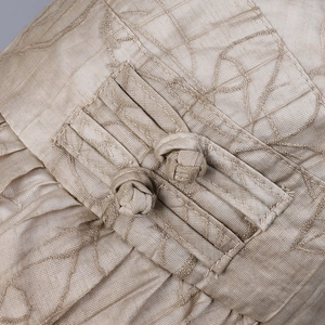 Detailed close-up of champagne silk fabric with embroidery and traditional knots