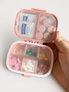 Detail view of pink portable 8-compartment pill box showing various tablets and textures