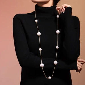Long collier élégant avec perles blanches et chaîne en acier inoxydable doré sur un mannequin