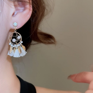 Close-up of bohemian dreamcatcher tassel earrings with gold alloy and white pearls