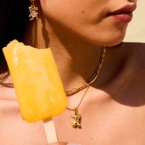 Golden bear pendant necklace and earring set with crystals on a female model
