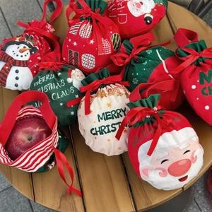 Christmas drawstring gift bags featuring festive Santa and snowman patterns on a wooden table