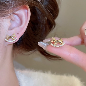 Vue détaillée des boucles d'oreilles cheval à bascule dorées serties de zircons brillants
