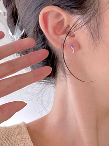 Close-up of minimalist heart stud earring with blue zircon on earlobe for elegant style