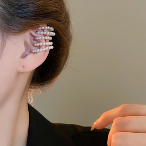 Close-up of a multi-layer pearl ear cuff with silver metal base worn by a model