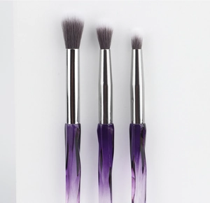 Detail of three eye brushes with purple wave handles and grey gradient bristles