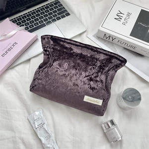 Detail of purple velvet cosmetic bag with Sozakka label on a stylish vanity desk