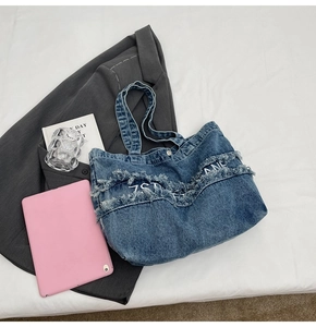 Détail du cabas en jean bleu avec bords à franges, broderie ZANE et bandoulière interne