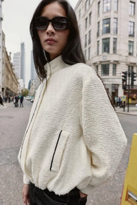 Detailansicht der cremefarbenen Tweed-Jacke mit schwarzer Paspelierung und Textur