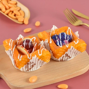 Artificial fruit Danish pastry models with berries and icing on wooden board